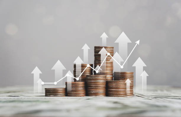 This image visually represents financial growth or investment returns. It features stacks of coins arranged in increasing height, symbolizing accumulating wealth or profit. Overlaying the coins are upward-pointing arrows and a line graph, reinforcing the idea of positive financial trends, economic progress, or successful business performance.